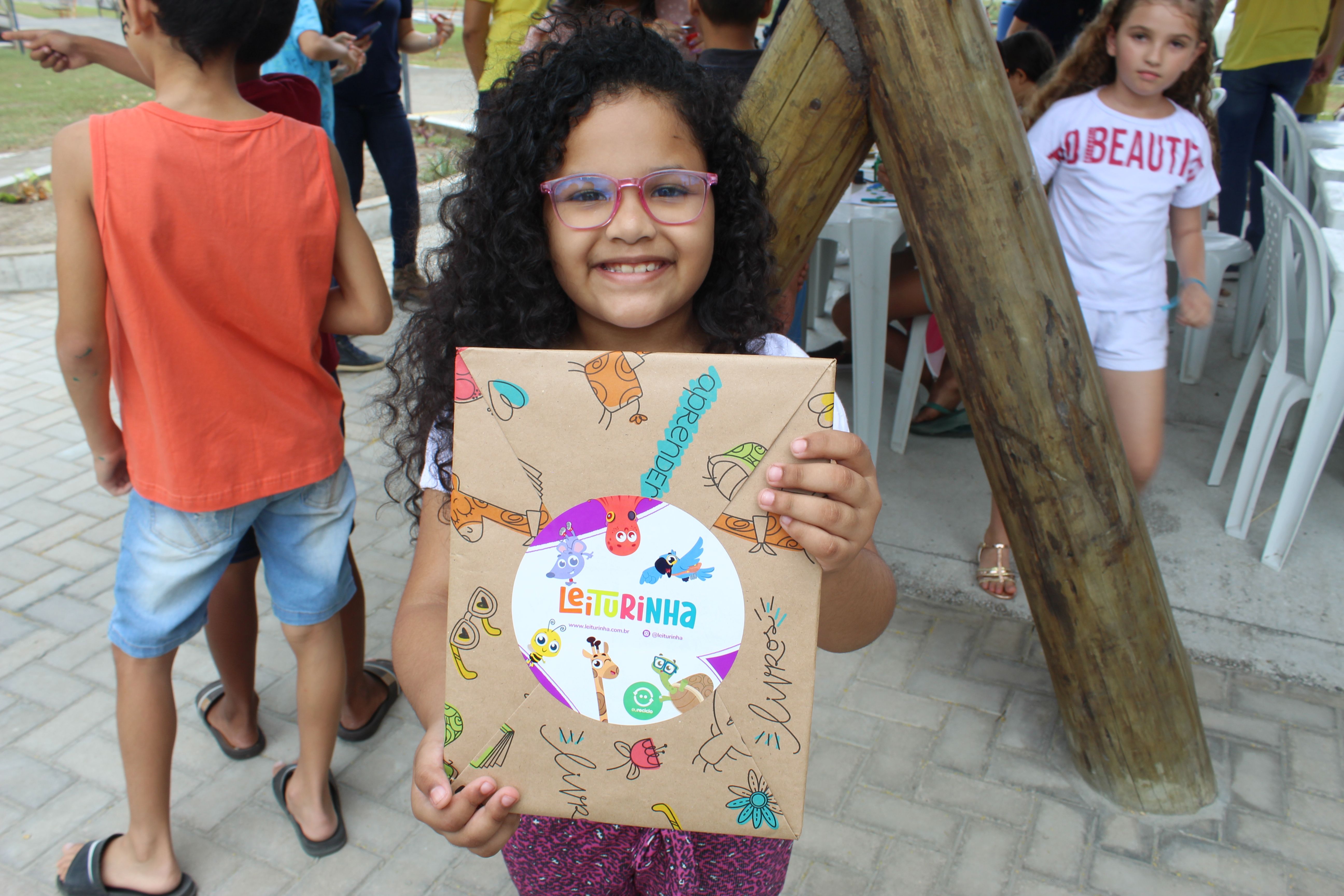 Imagem de uma menina segurando seu livro recebido de presente