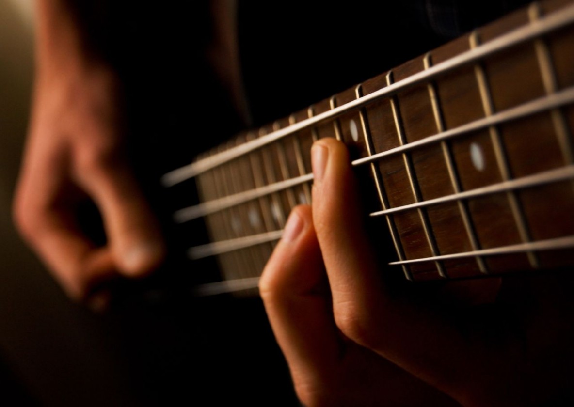 up close fingers on electric bass fretboard