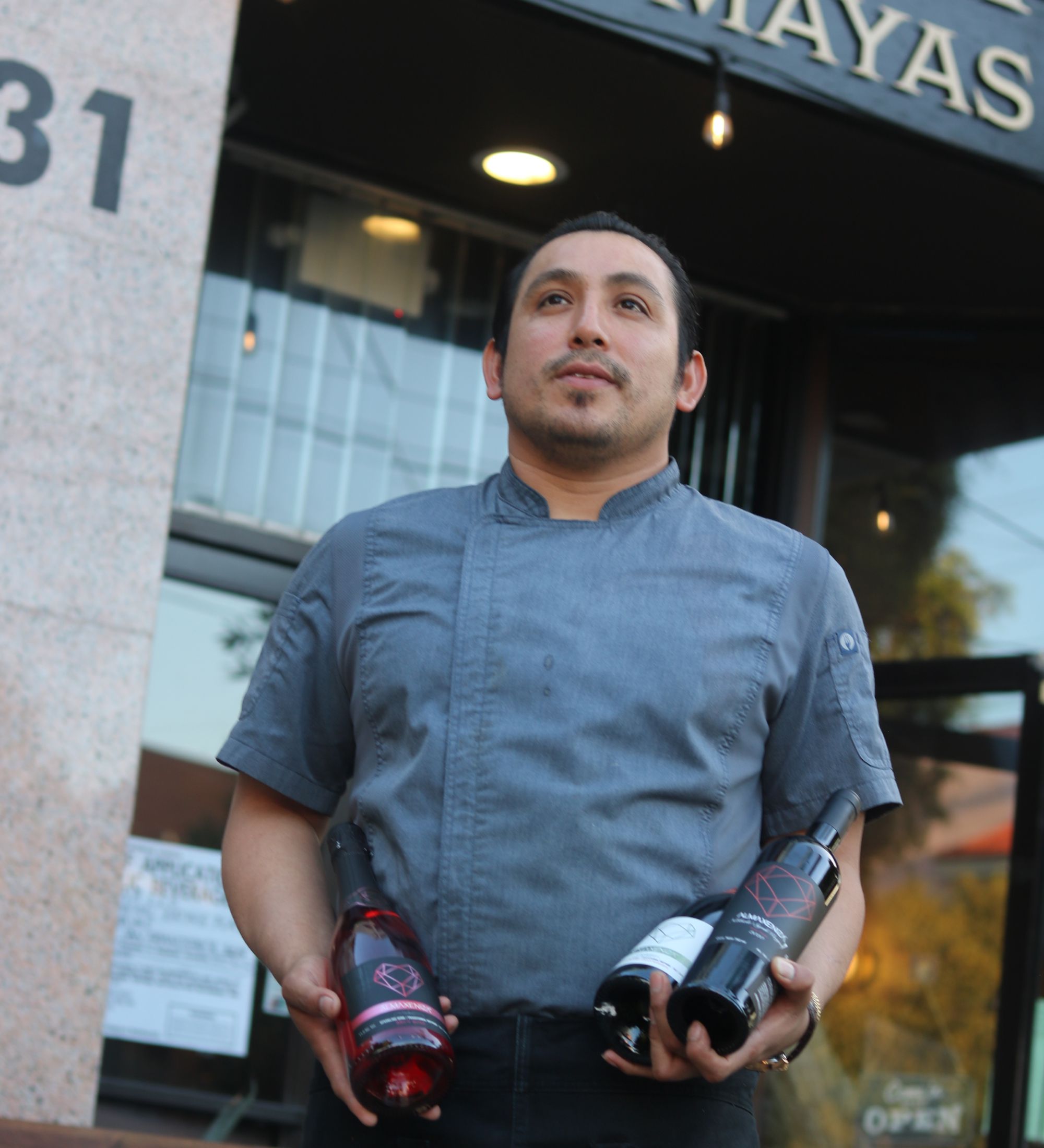 Photo of Morgan holding Mexican wines in front of Cantina Los Mayas