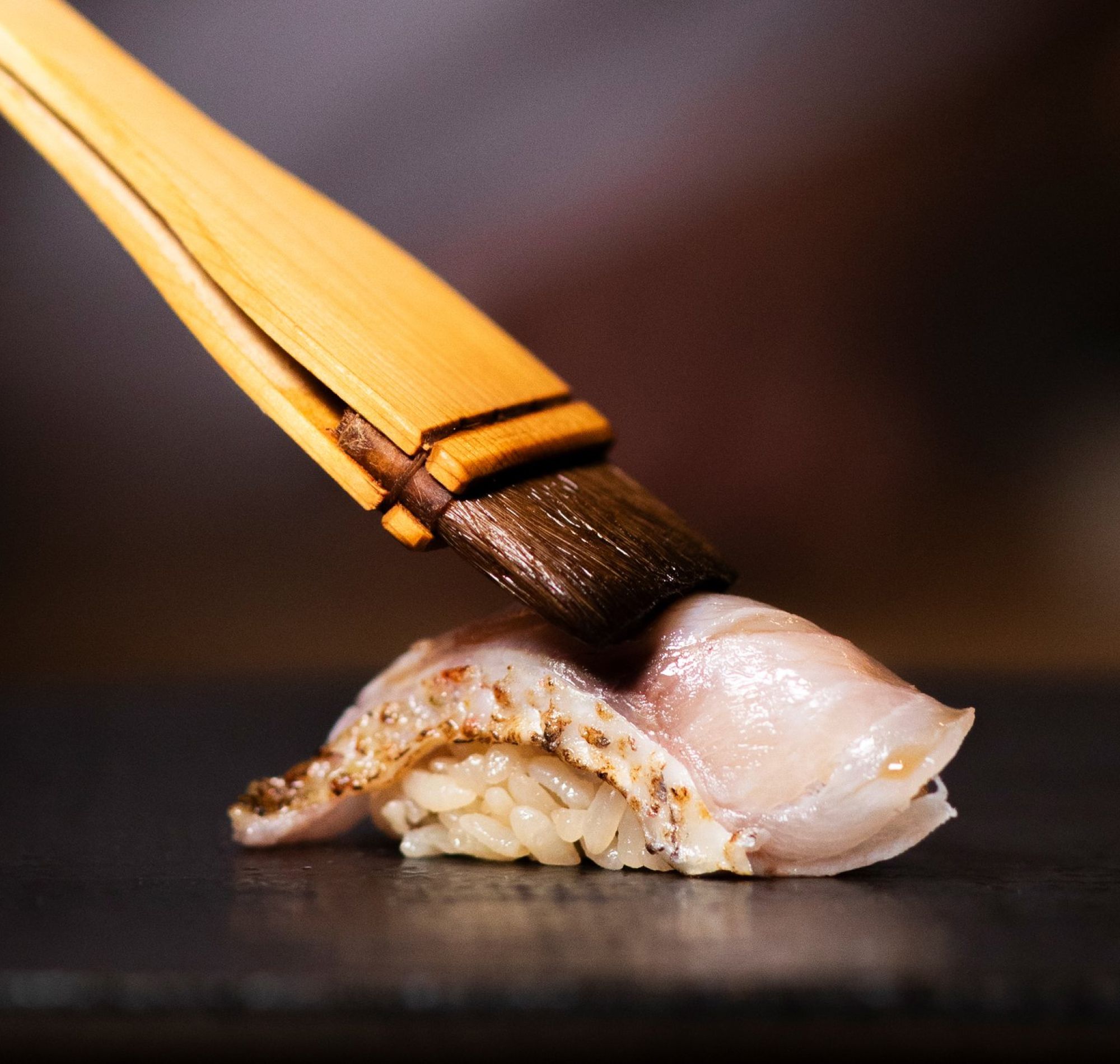 Chef brushing sauce on a piece of nigiri