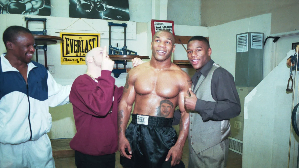 Floyd Mayweather Sr., Angel Manfreddy, Mike Tyson, and Floyd Mayweather Jr. pose in a boxing gym in 1999.