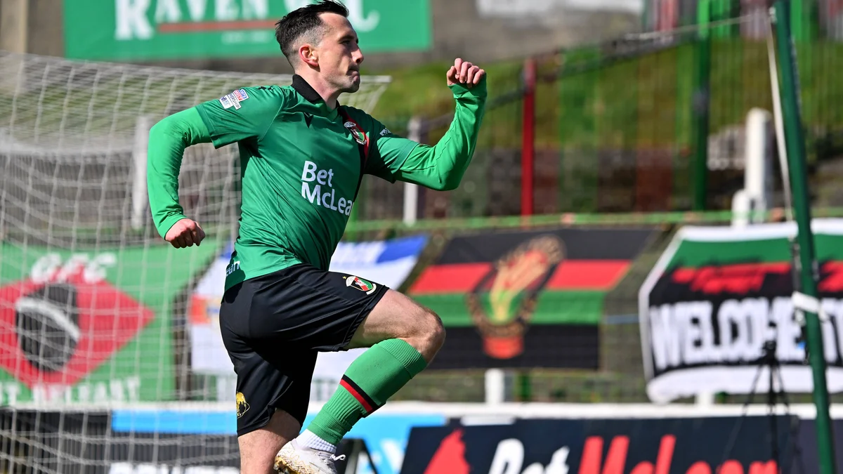 Glentoran midfielder Aaron McEneff celebrates scoring a goal during a football match.