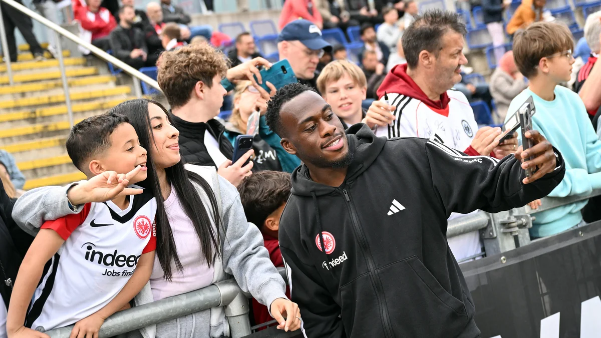 Arnaud Kalimuendo, wearing an Eintracht Frankfurt jersey, stands on a football pitch.