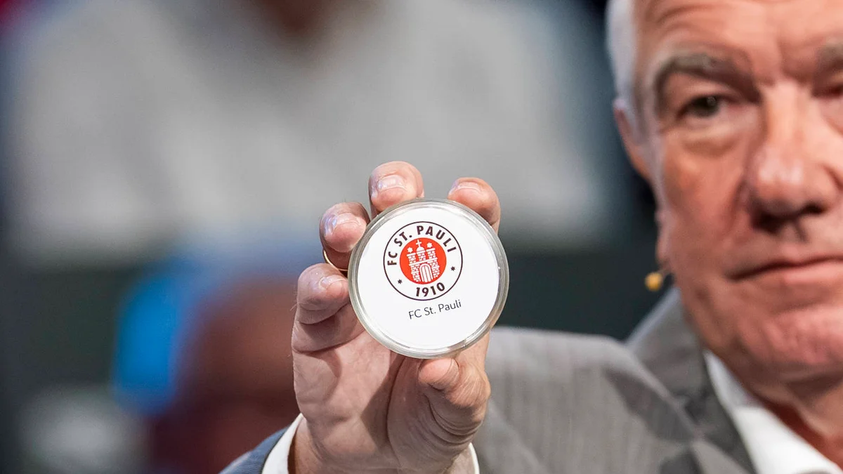 A hand holds a draw ball with 'FC St. Pauli' during the DFB Cup draw at the German Football Museum.