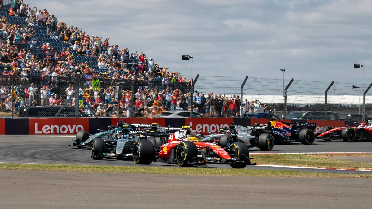 Multiple Formula 1 cars, including Mercedes, Ferrari, McLaren, and Red Bull, race on the Silverstone Circuit.