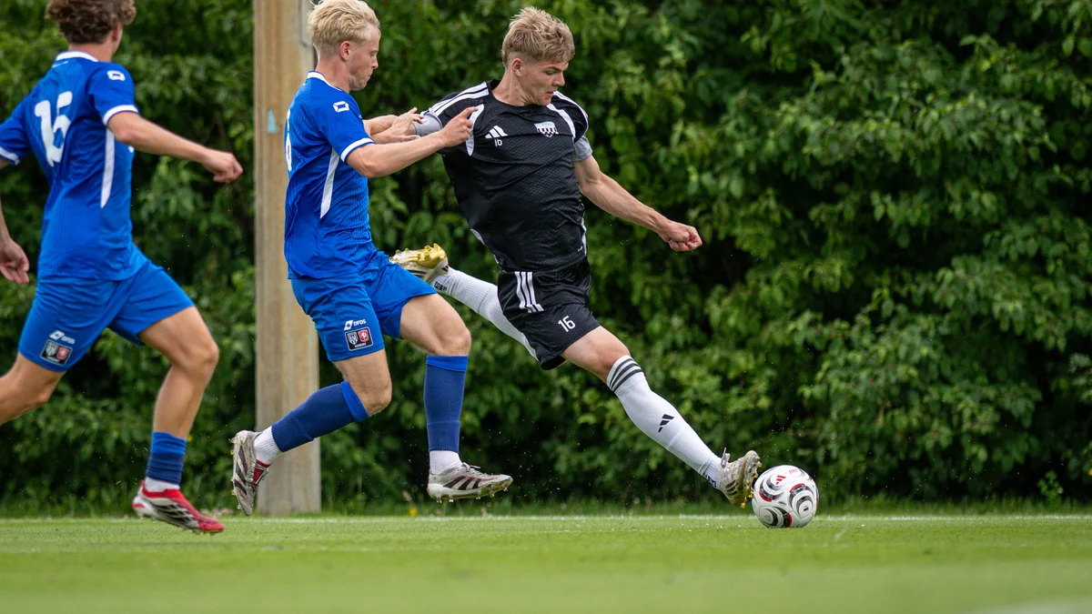 Football players from 1.FC Bocholt (black) and FC Twente Enschede U21 (blue) compete during a friendly match.