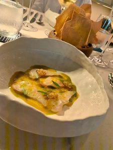 Pescado servido con salsa cítrica y guarniciones de textura crujiente.