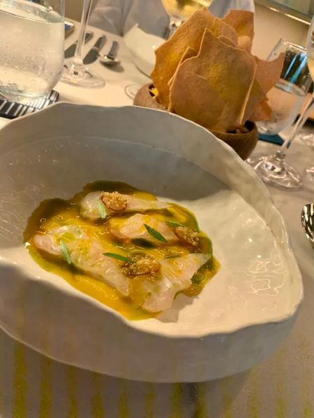 Pescado servido con salsa cítrica y guarniciones de textura crujiente.