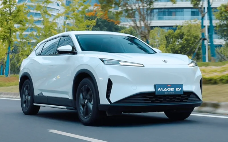 Dongfeng Mage EV blanco, SUV eléctrico moderno en movimiento por calle arbolada.