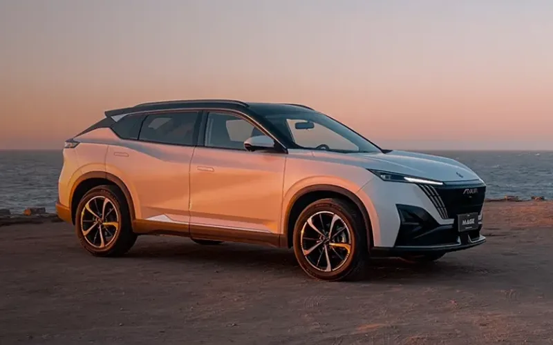 Dongfeng Mage SUV blanco con techo negro estacionado junto al mar al atardecer.