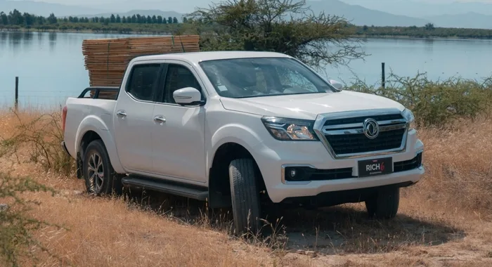 Dongfeng Rich 6 Euro VI blanca estacionada en campo con lago de fondo, mostrando su capacidad de carga.