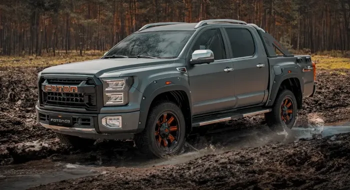 Foton G9 pickup gris oscuro en acción off-road, atravesando lodo. Muestra su capacidad todoterreno 4x4.