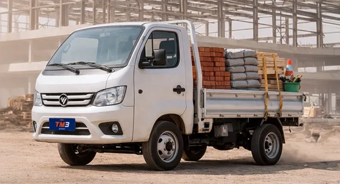 Foton TM3 Cabina Simple blanco con carga de materiales en obra. Camión de trabajo versátil.