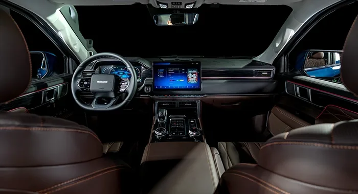 Lujoso interior Foton V9 con asientos de cuero marrón, pantalla táctil central, tablero digital y volante multifunción.