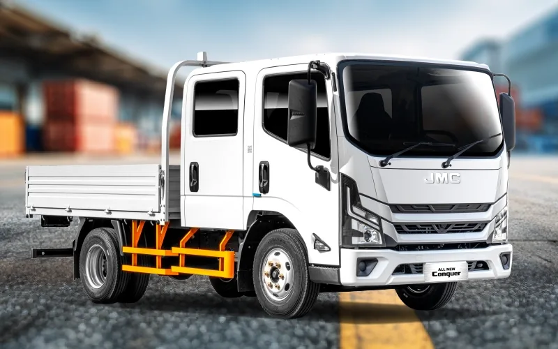 JMC Conquer 4.5 Doble Cabina Euro 6 blanco, camión de plataforma en fondo industrial.