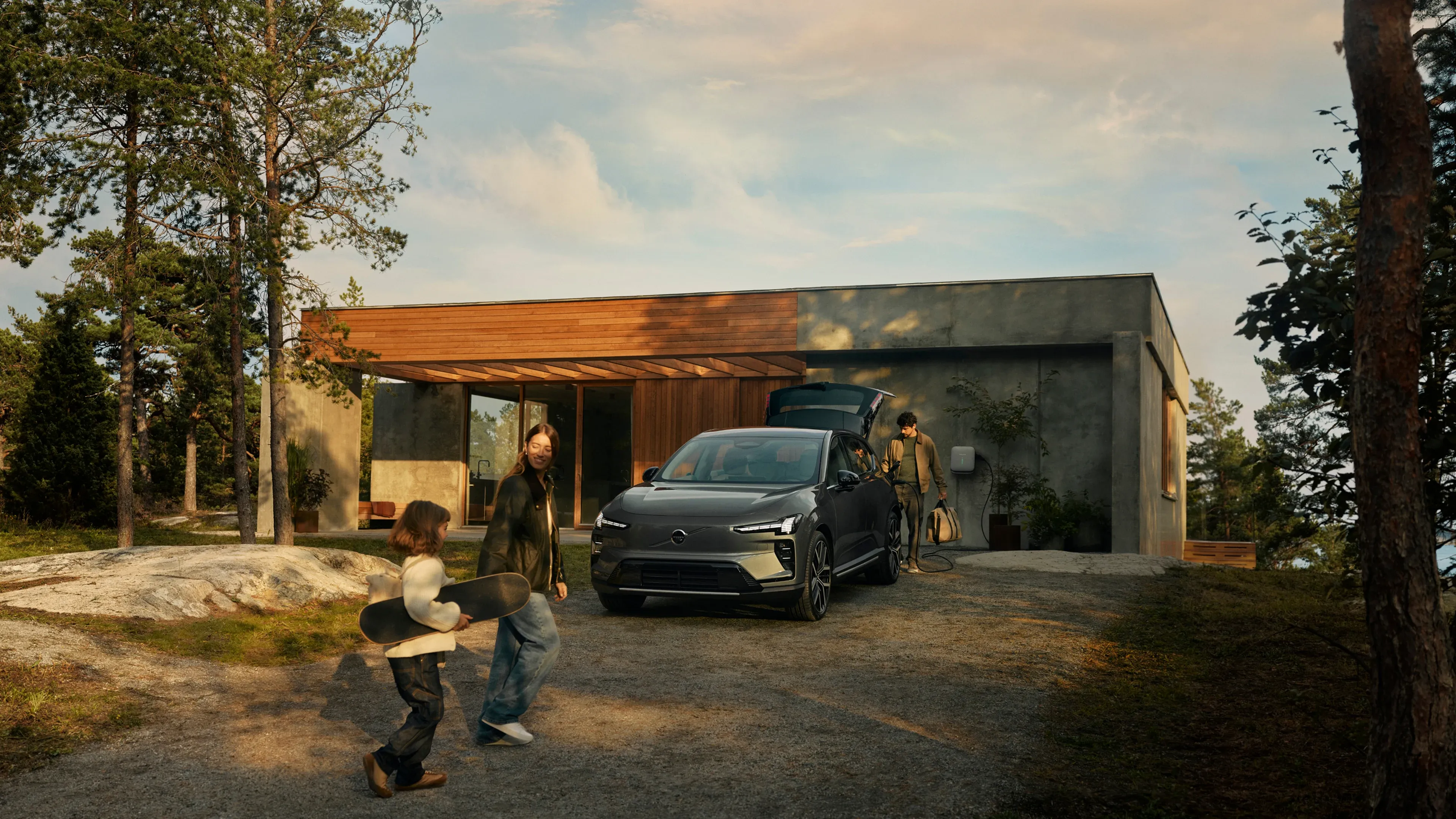 Family unloads car at a modern home as children play in the driveway.