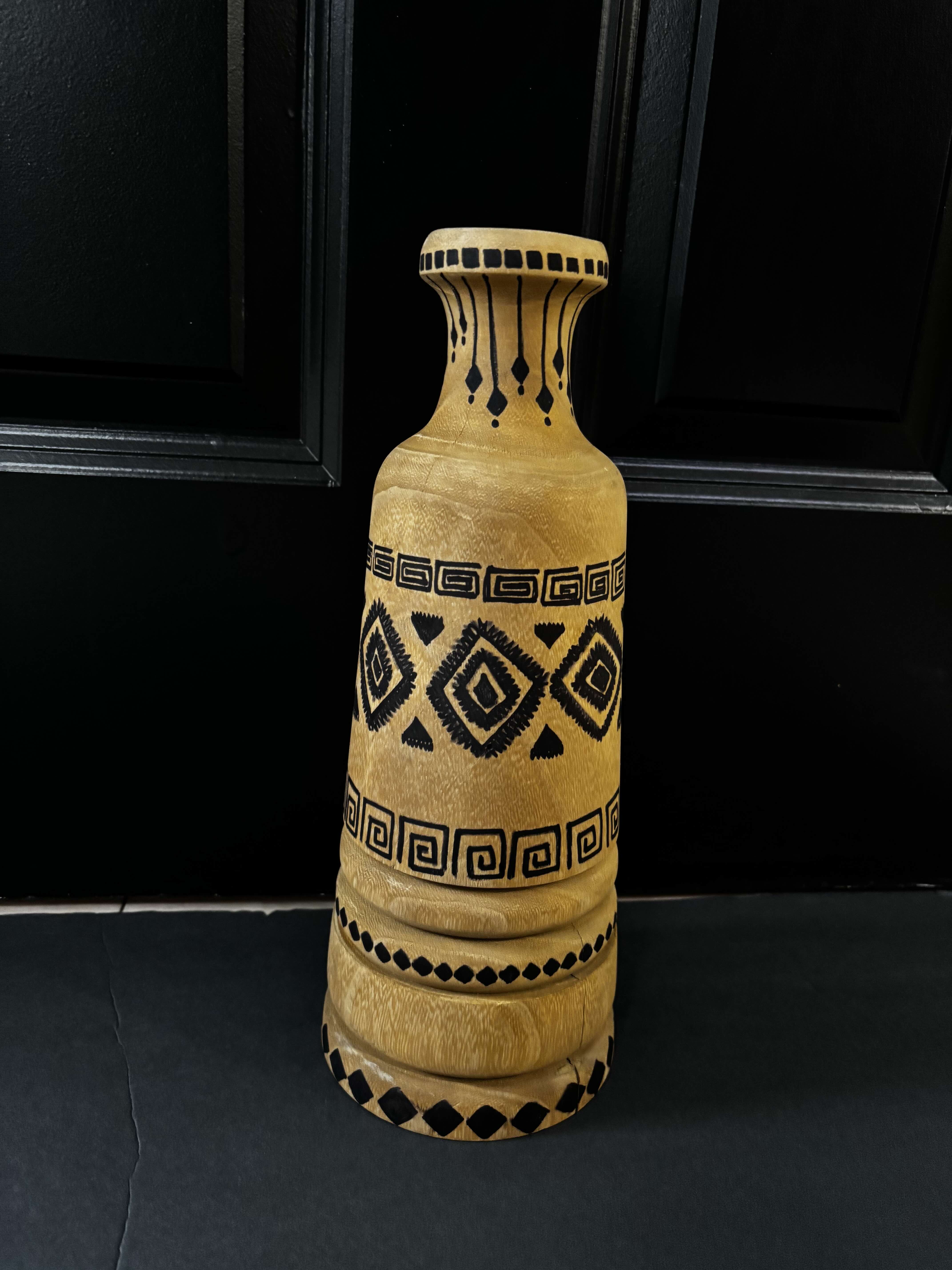 A tall wooden vase with black geometric patterns.