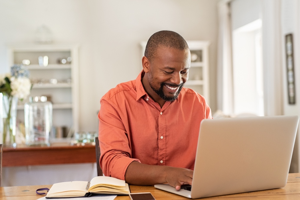 Man in orange shirt working from home using team collaboration software