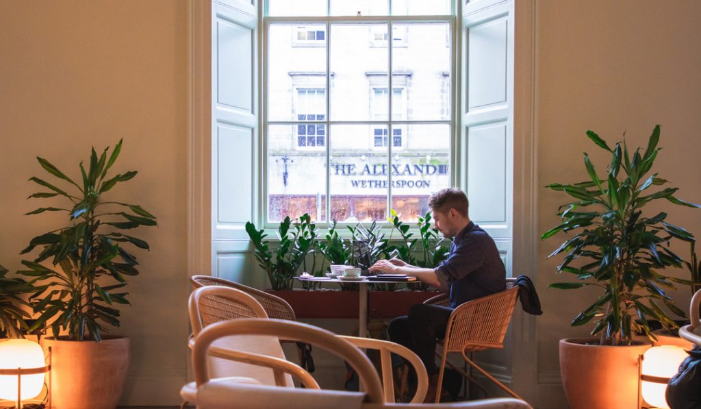 Millennial working in coffee shop on flexible work basis