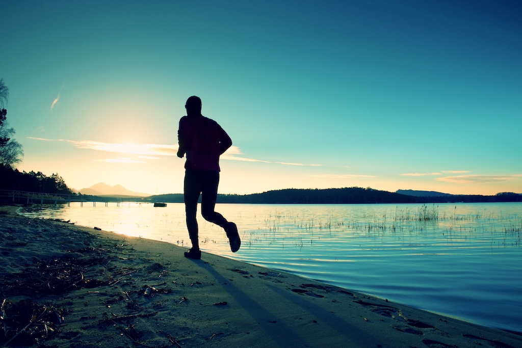 Man running along beach as sun rises being healthy working Anywhere