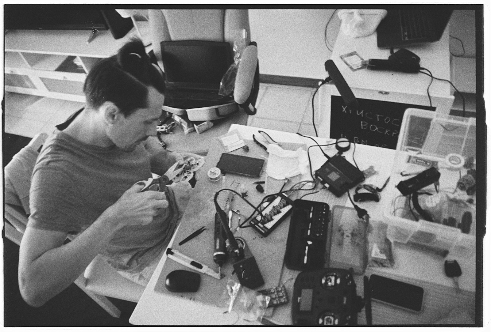 man working on electronic components at a cluttered workbench