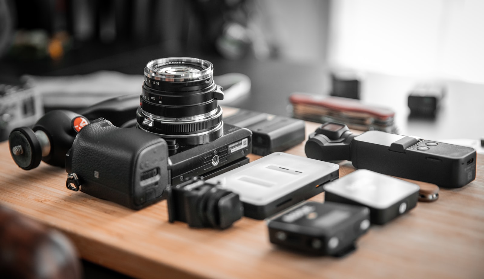camera body, lens, and various accessories arranged on a wooden table