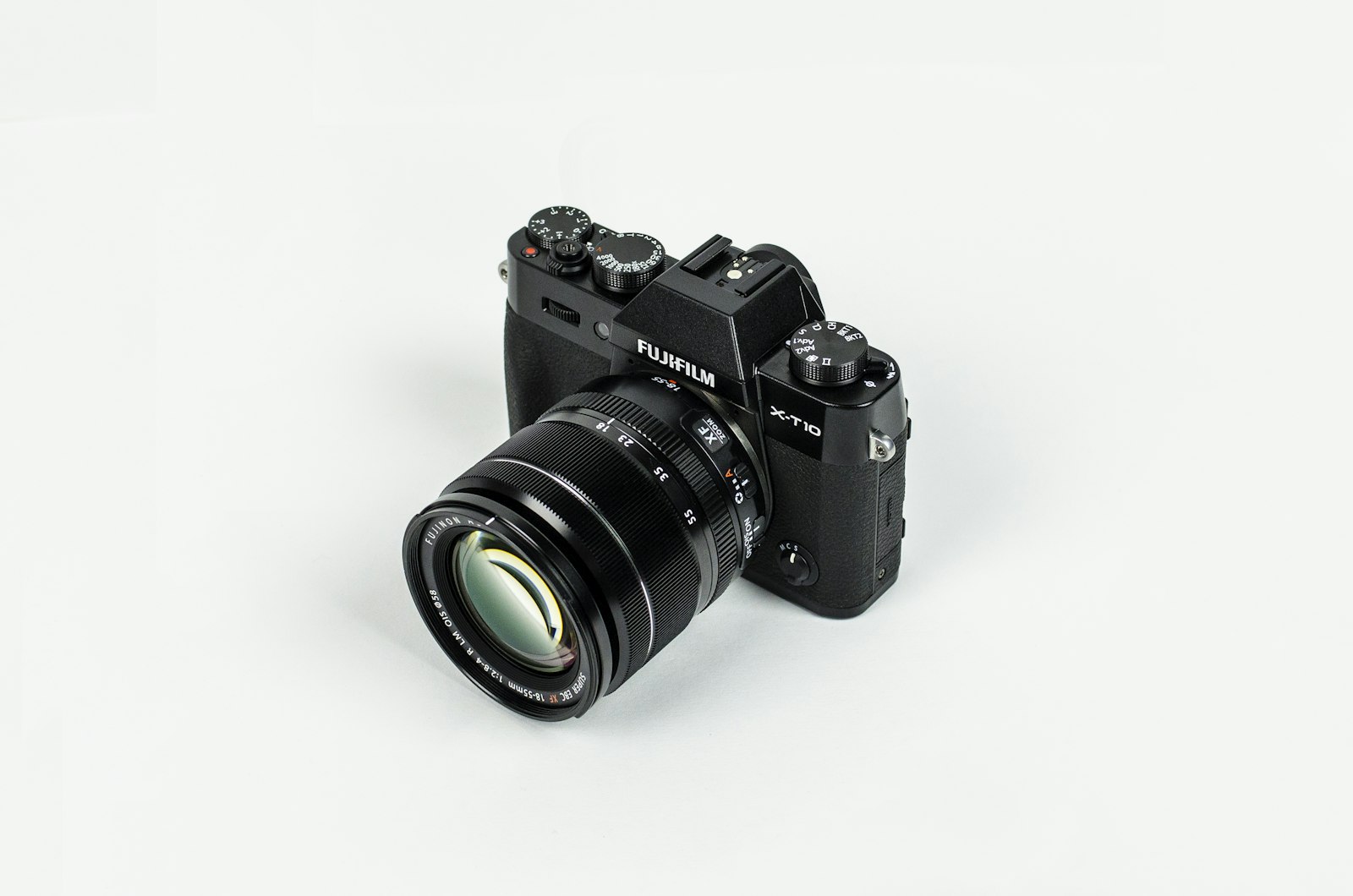 black mirrorless camera with attached lens on a white surface