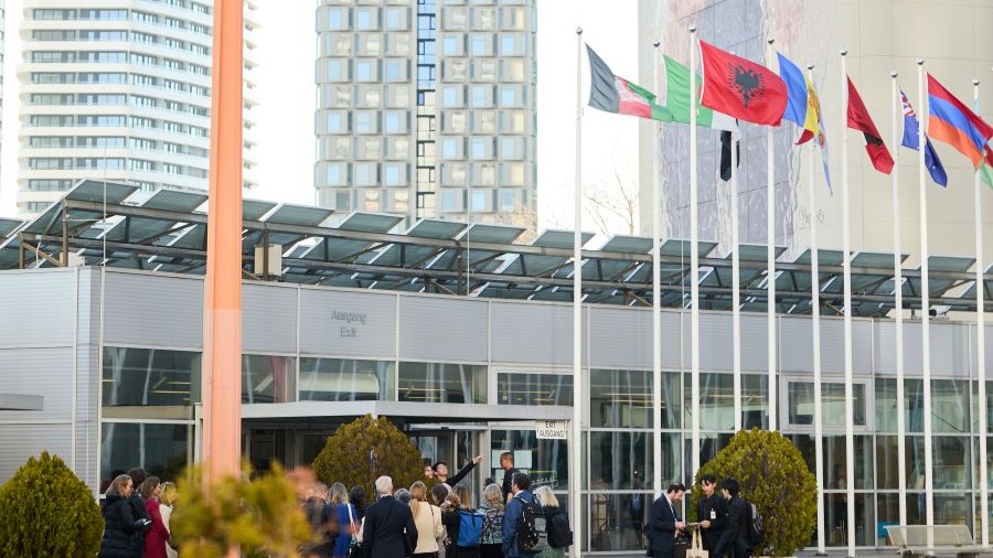 A photo that shows a small crowd inside the VIC building complex; different flags are waving in the wind.