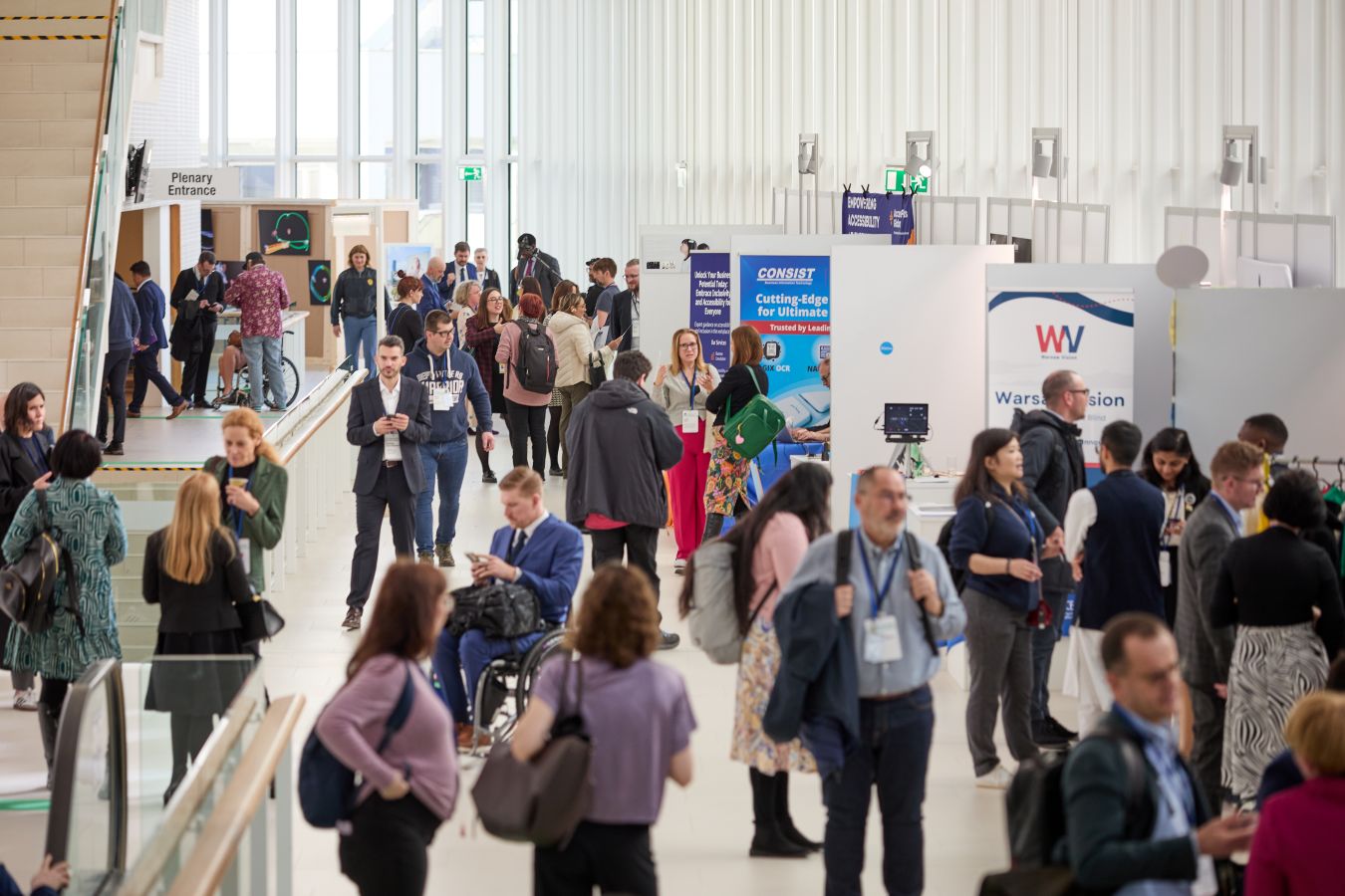 People walking down one of the busy corridors; some wearing suits, others just shirts, indicating the warmer temperatures inside the venue.