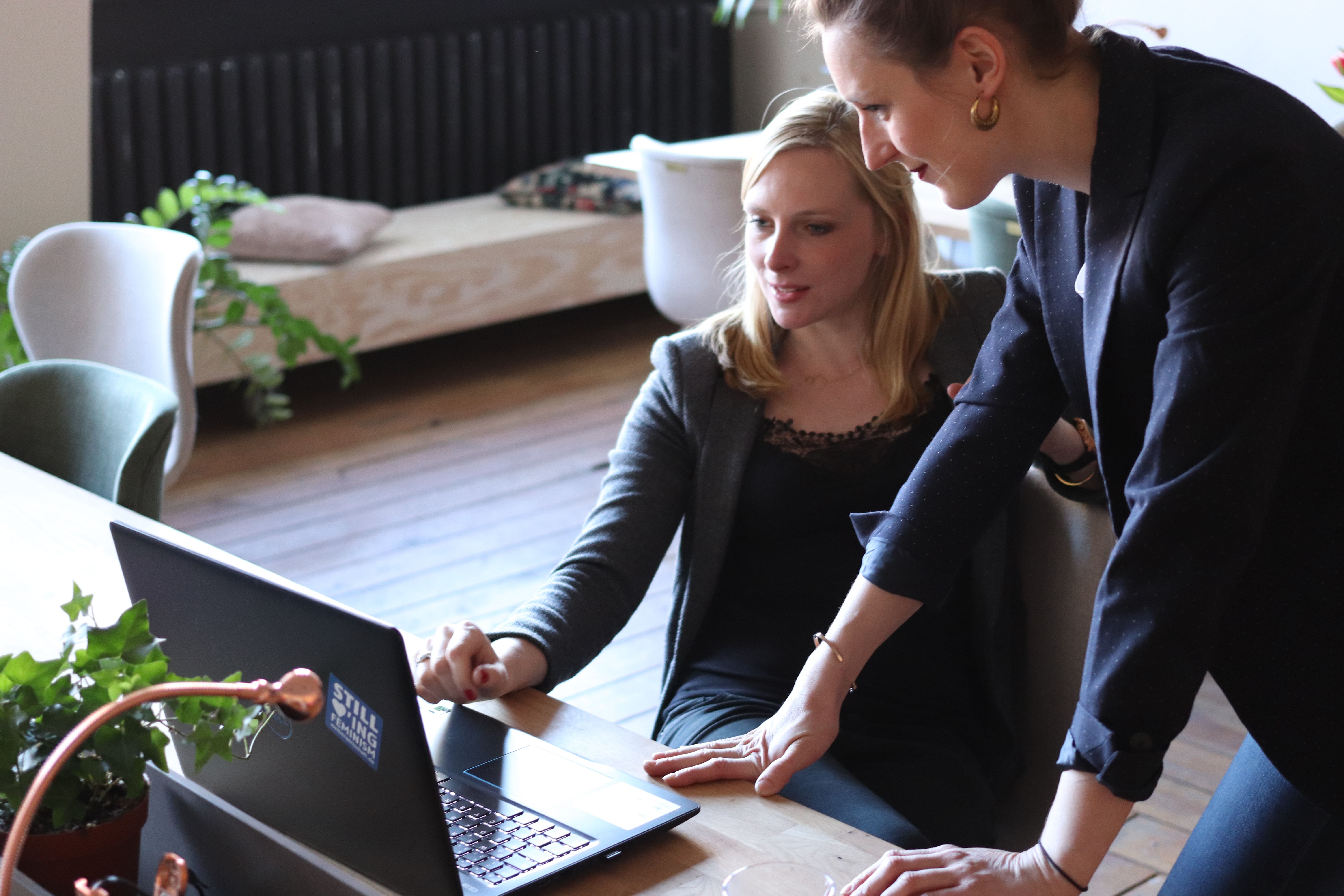 Two women at a desk looking at a laptop screen.