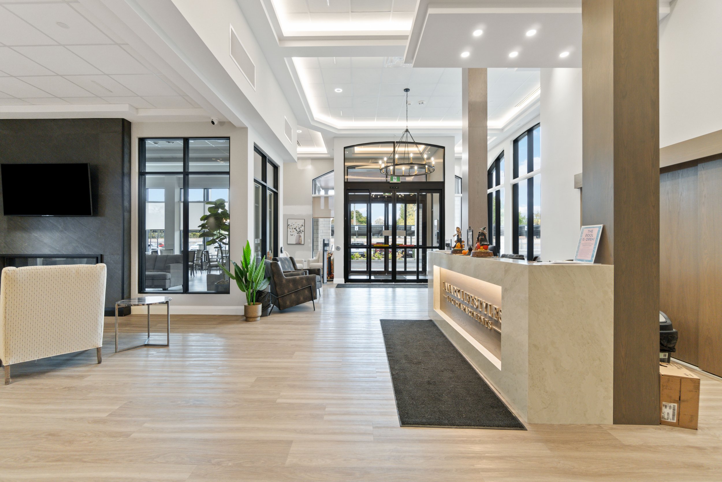 Modern hotel lobby with a reception desk, seating area, and large windows.