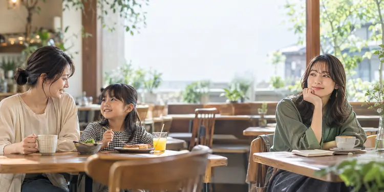 日差しの入るカフェで会話を楽しむ母娘と、くつろぐ女性