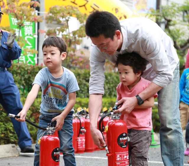 災害時の火災対応訓練  消火訓練をするパパとこども