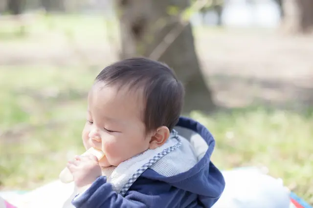 外でおやつを食べる赤ちゃん