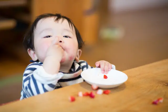 おやつを手づかみで食べる赤ちゃん