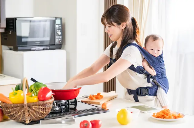 子どもをおんぶして食事の支度をするママ