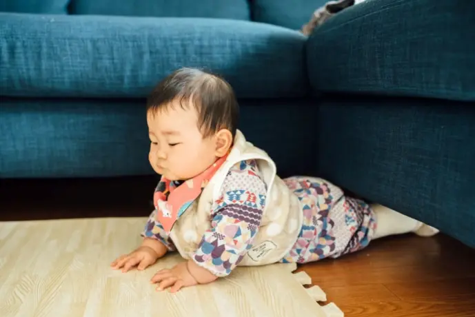 ソファの隙間に入って遊ぶ赤ちゃん