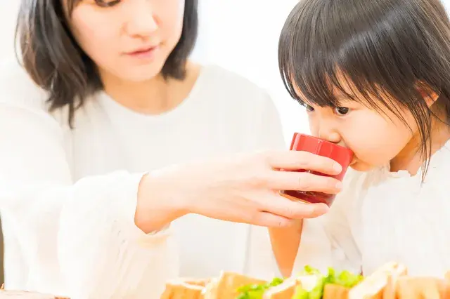 コップで水をのむ女の子