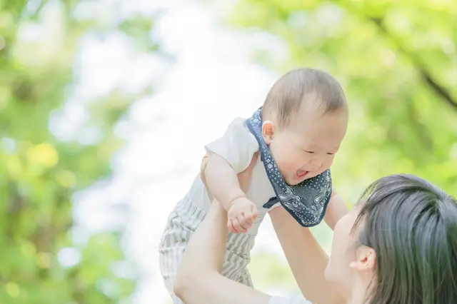 赤ちゃんを高く持ち上げる女性