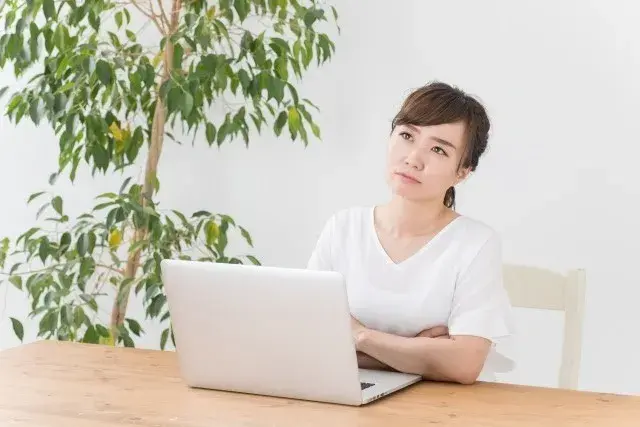 PCの前で悩む女性