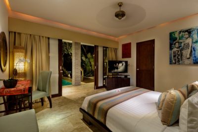 Luxurious Balinese bedroom with king bed, private pool view through open sliding doors, and tropical decor.