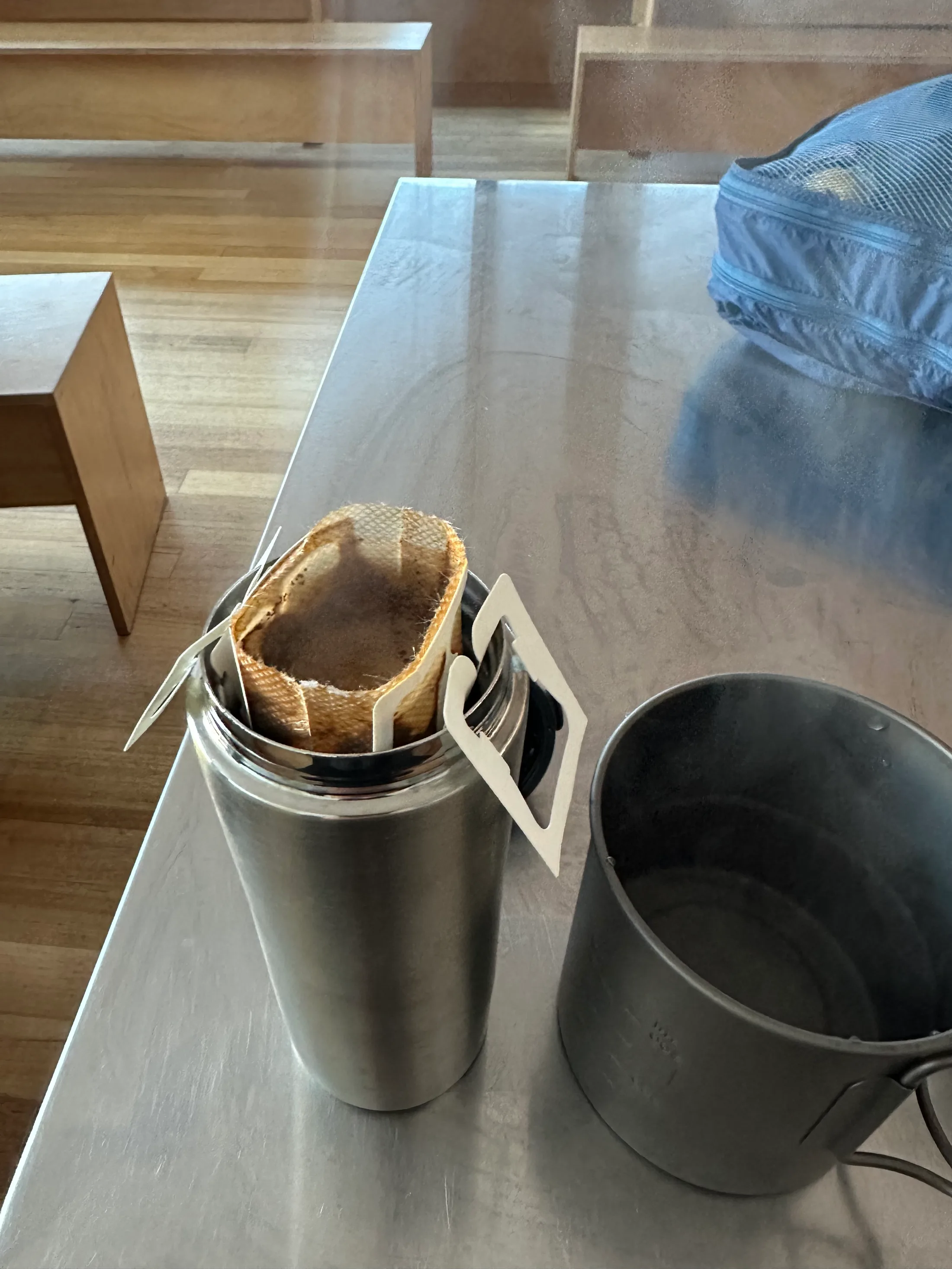 A steaming drip coffee inside Waterfall Valley Hut — the small ritual that makes a cold hut feel like camp.