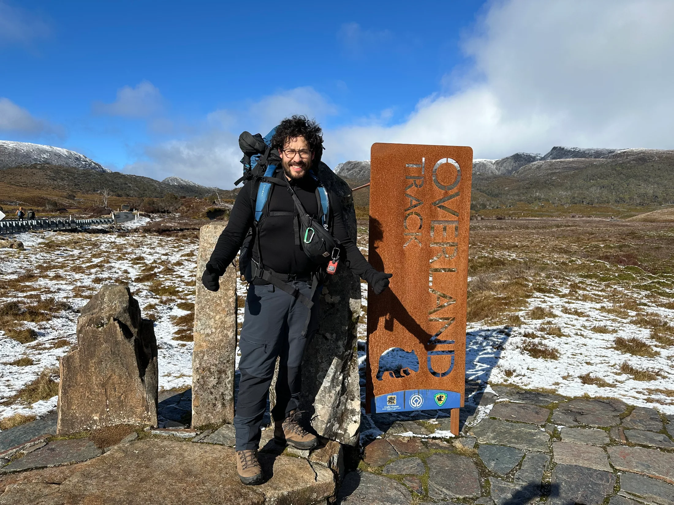 The Overland Track signpost at Ronny Creek, with a dusting of fresh snow on the boardwalk.