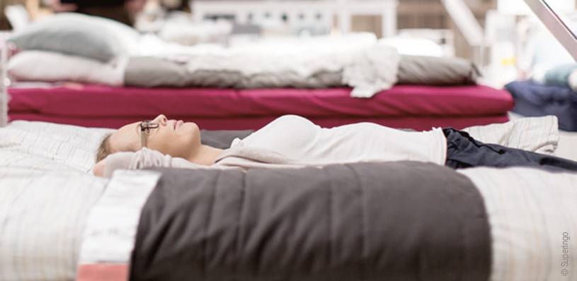 Foto: Eine Frau liegt mit dem Rücken auf einem Bett im Matratzengeschäft