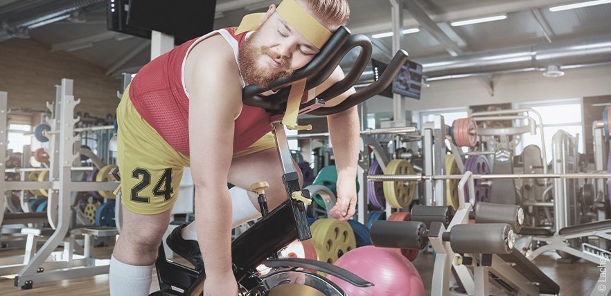 Symbolfoto zur Muskelregeneration: In einem Fitnesstudio schläft eine Person auf einem Radtrainer 