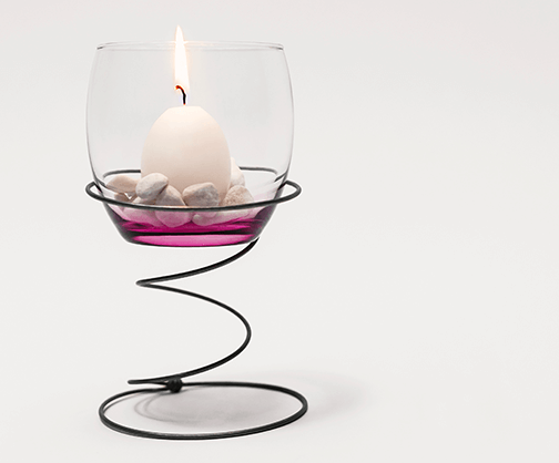 Foto: Eine einzelne Bonellfeder hält ein Glas mit brennender Kerze darin.