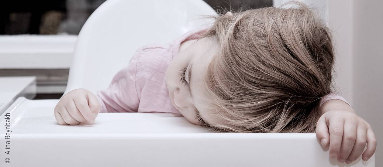 Foto: Ein Kind schläft im Hochstuhl.