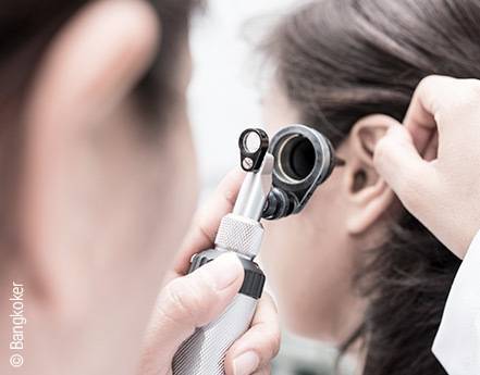 Foto: Ein Arzt untersucht mit einem Otoskop das Ohr einer Patientin.