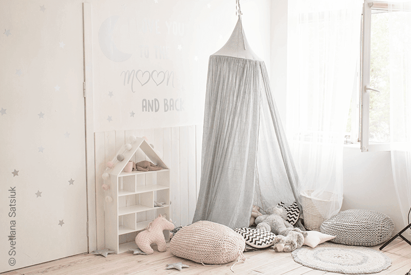 Foto: ein Kinderzimmer in hellen Grau- und Weißtönen, in der Mitte ein Baldachin mit einem horizontal aufgehängten Ring als Aufhängung für den Stoff