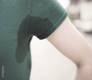 Foto: Eine an den Achseln durchnässtes T-Shirt zeigt, dass die Person, die es trägt, stark schwitzt.